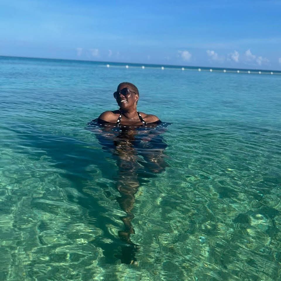 Carol standing in clear turquoise shallow water, smiling