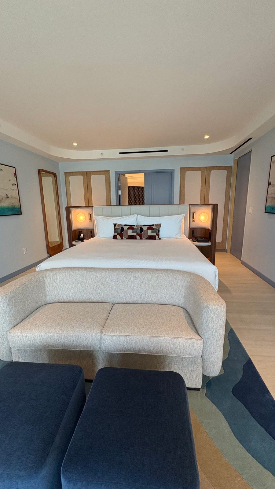 A guest room with a made bed, a sofa and warm lamplight
